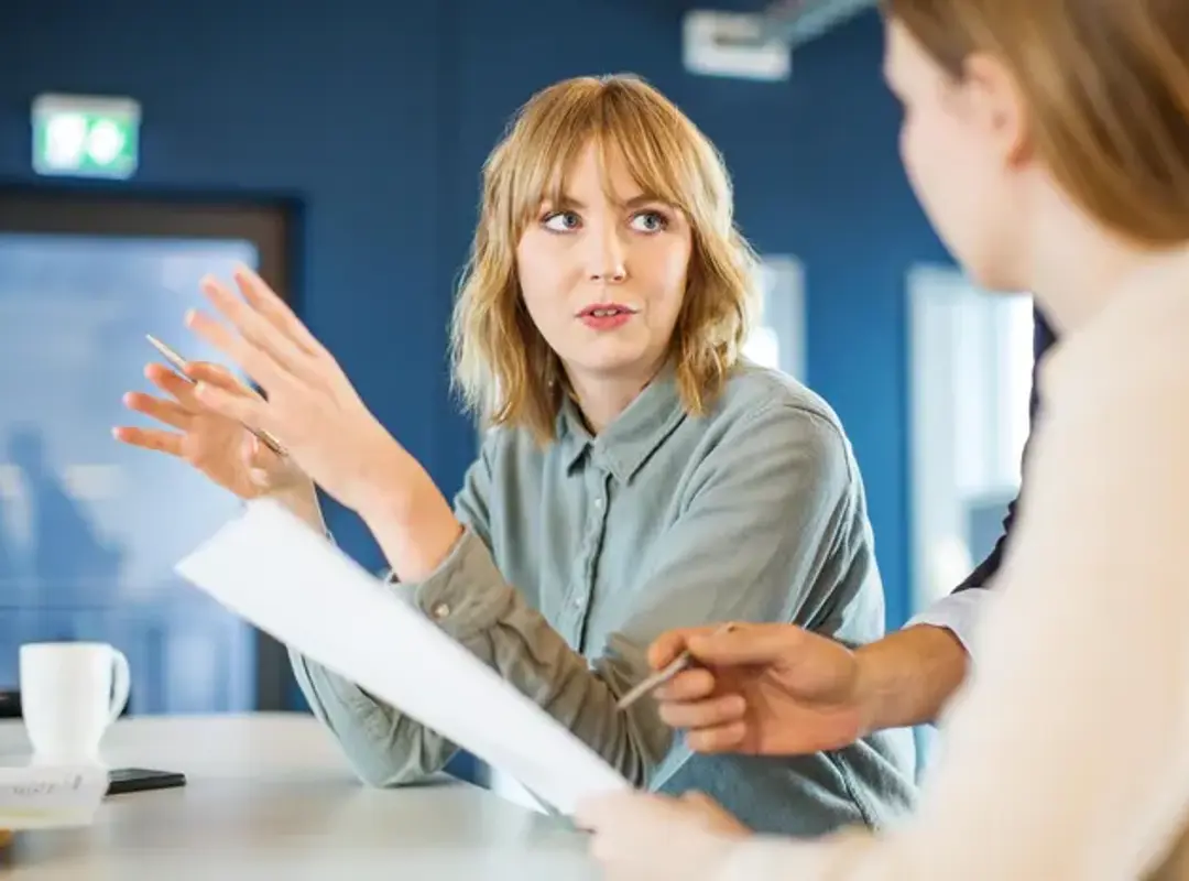 Two people in meeting holding papers