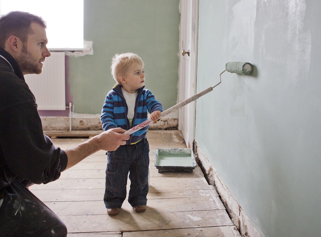 Parent And Child Painting A Wall With A Roller Brush