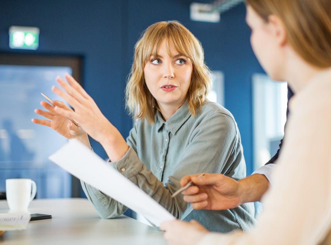 Two People In A Meeting Holding Papers