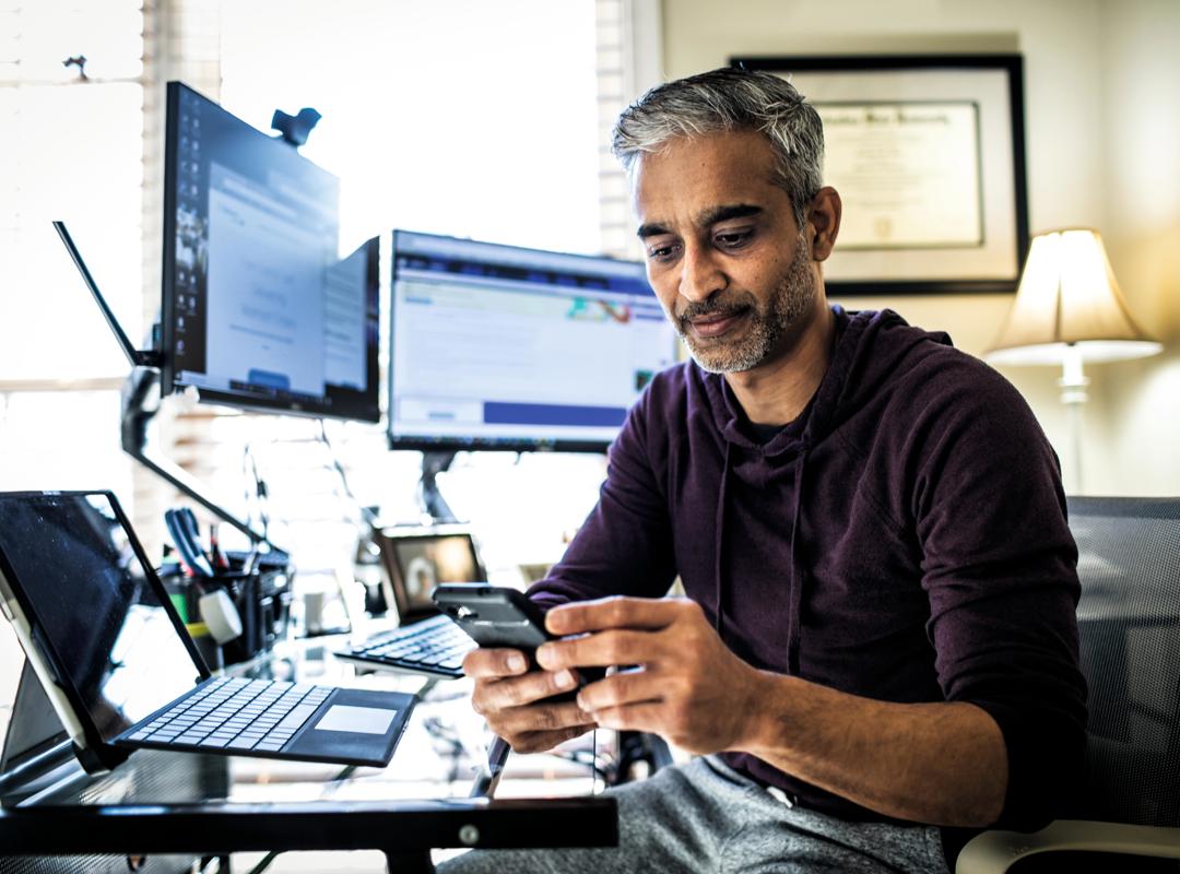 Man On His Phone At His Desk With Computers