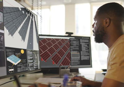 Man Looking At Computer With Solar Panels On Screen